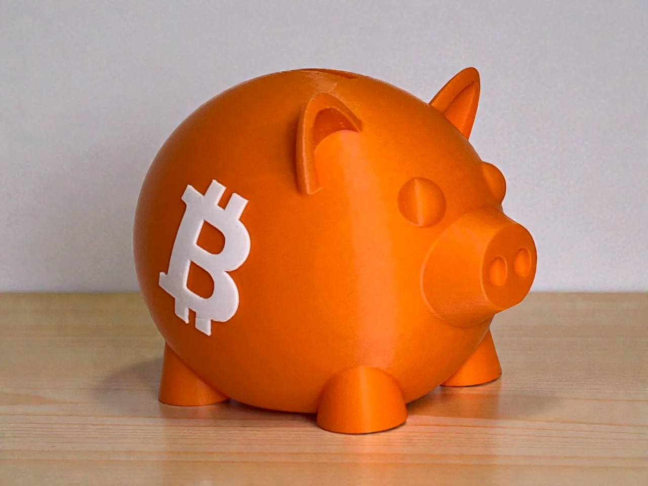 Orange 3D-printed Bitcoin piggy bank with a white Bitcoin emblem